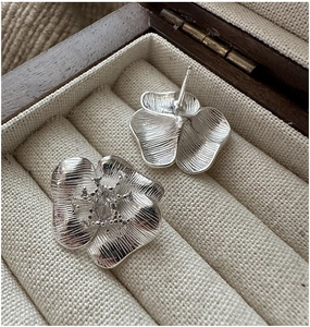Macro detail of S925 sterling silver flower earrings with radiant texture and crystals
