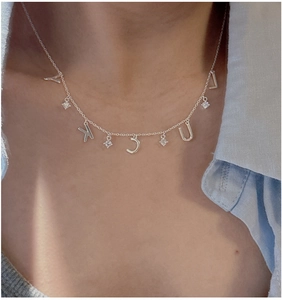 Macro detail of S925 silver LUCKY letter necklace with zircon pendants on neck