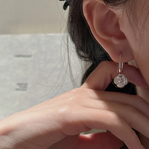 Élégantes boucles d'oreilles fleur camélia en argent S925 portées par un mannequin chic