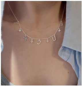 Close-up of S925 silver Lucky letter pendant with sparkling cubic zirconia on neck