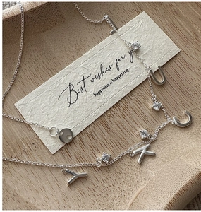 Macro detail of S925 silver LUCK pendant with sparkling stones on a delicate chain