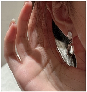 Détail macro de boucles d'oreilles rayées en argent avec cristal portées par un modèle