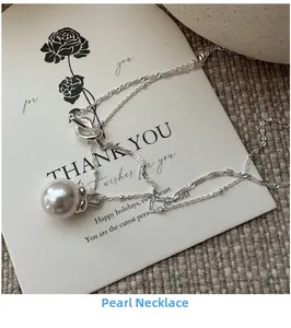 Detailed view of single large white pearl pendant on a fine silver twist chain necklace