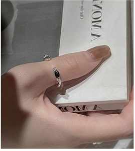 Détail d'une bague torsadée en argent avec extrémités coniques noires et zircons brillants