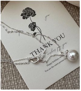 Detail of S925 silver double-layer necklace featuring a large pearl and metal knot link