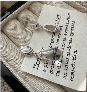 Détail macro de boucles d'oreilles en argent 925 avec sphère rayée et goutte de cristal