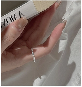Close-up of minimalist S925 sterling silver textured band ring on finger with soft aesthetic