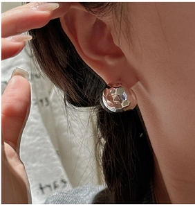 Macro shot of silver textured rhombus earrings with lava hammer finish on a model