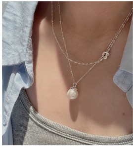 Close-up of double-layered S925 silver necklace with wave chain and pearl pendant
