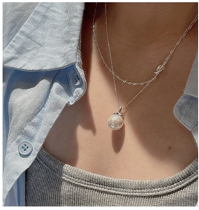 Macro detail of silver double-layered necklace featuring a lustrous pearl and twisted rope chain