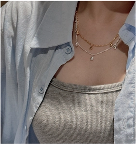 Détail du collier S925 argent à deux rangs avec pendentifs goutte d'eau sur chemise bleue