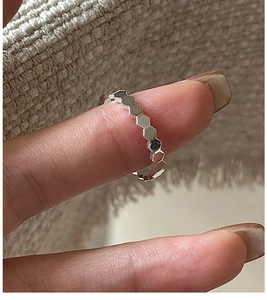 Close-up of a silver honeycomb geometric ring with hexagonal texture on finger