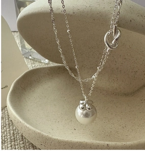 Macro shot of S925 sterling silver stamp and double-layered chain with a pearl pendant