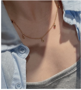 Détail d'un collier minimaliste doré avec plusieurs pendentifs goutte d'eau polis
