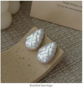 Macro view of teardrop stud earrings with woven texture and matte silver finish