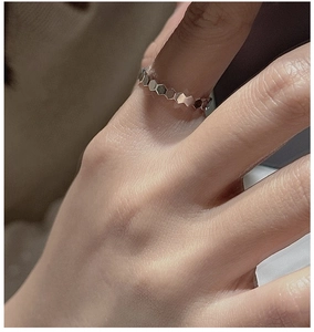 Macro shot of silver hexagonal honeycomb geometric ring on finger with detailed reflections