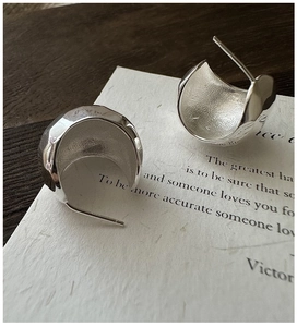 Close-up of S925 sterling silver earrings with textured hammered finish on white card