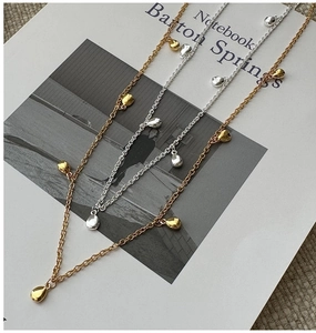 Détail de colliers superposés en argent S925 avec pendentifs gouttes d'eau sur carte