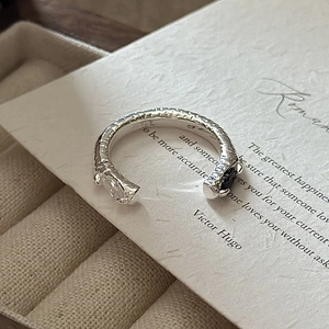 Bague en argent S925 avec texture martelée et zircons posée sur une carte à bijoux