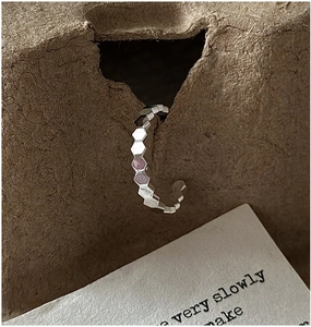 Macro shot of silver honeycomb textured ring displayed on vintage kraft paper card