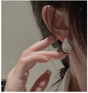 Detail of woven texture S925 sterling silver earrings shown on model ear