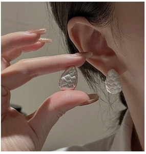 Macro detail of tear-drop woven silver earrings with a matte textured finish