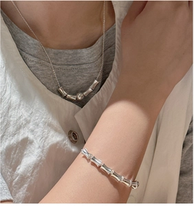 Detailed view of polished silver bamboo-style necklace and bracelet set on model