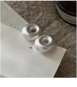 Macro shot of matte S925 sterling silver hollow donut earrings on retro display card