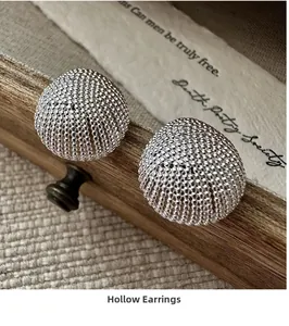 Macro shot of silver hollow ball earrings with intricate beaded texture on a vintage backdrop