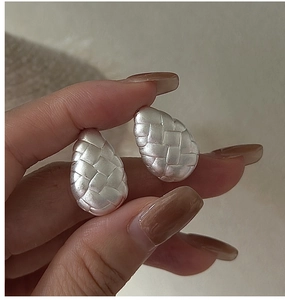 Close-up of S925 sterling silver drop earrings with vintage woven texture held in hand
