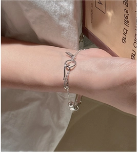 Detail of silver bamboo style link bracelet with large circular clasp on a model's wrist