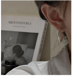 Detail of silver hoop earrings with spiral texture shown on model in a soft setting