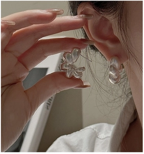 Macro view of abstract twisted silver hoop earrings with a matte liquid metal texture