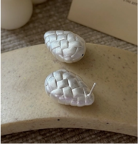 Macro shot of silver woven teardrop earrings with matte texture on minimalist display
