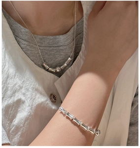 Detail showing 925 silver bamboo link necklace and bracelet set on model wearing white shirt