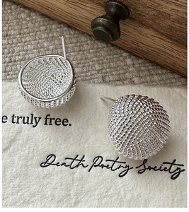 Macro detail of silver spherical stud earrings with intricate woven honeycomb texture
