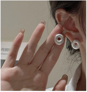 Close-up of matte silver hollow donut earrings worn to show style and dimensions