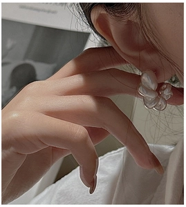 Close-up of matte white flower stud earrings in 925 sterling silver on model ear