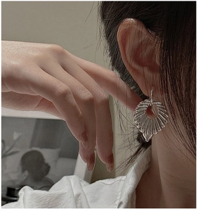 Detailed view of S925 sterling silver hollow earrings with radial texture on model's ear