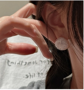 Detail of S925 sterling silver woven ball stud earrings worn on model's earlobe