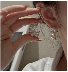 Detailed view of matte silver twisted hoop earrings with a sculptural hollow design