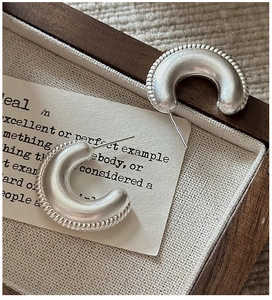 Detail of matte S925 sterling silver C-shaped earrings with braided rope texture edge