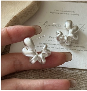 Macro view of matte 925 sterling silver hollow earrings with twisted knot design
