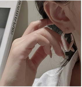 Gros plan d'un modèle portant des boucles d'oreilles géométriques carrées en résine