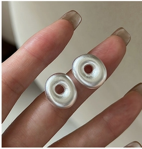 Close-up of minimalist S925 sterling silver matte hollow donut hoop earrings held by hand