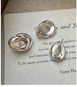 Macro detail of silver S925 drop earrings with matte finish on vintage paper background