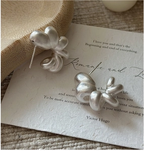 Macro detail of matte S925 silver hollow twisted earrings with retro grainy texture