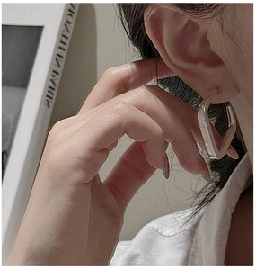 Gros plan de boucles d'oreilles carrées minimalistes en argent sur un modèle coréen