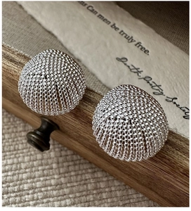 Detailed close-up of S925 silver stud earrings with vintage beaded texture on wooden box