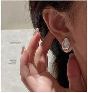 Macro view of minimalist S925 sterling silver irregular drop earrings on an ear model